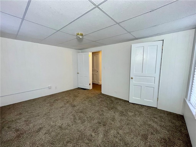 basement featuring dark colored carpet and a paneled ceiling