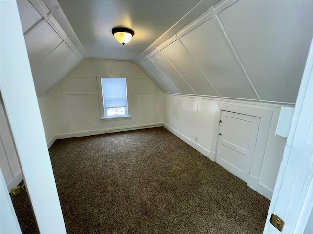 additional living space with dark carpet and vaulted ceiling