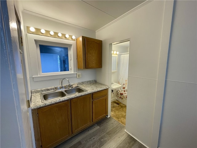 bathroom with hardwood / wood-style floors, ornamental molding, sink, and tile walls