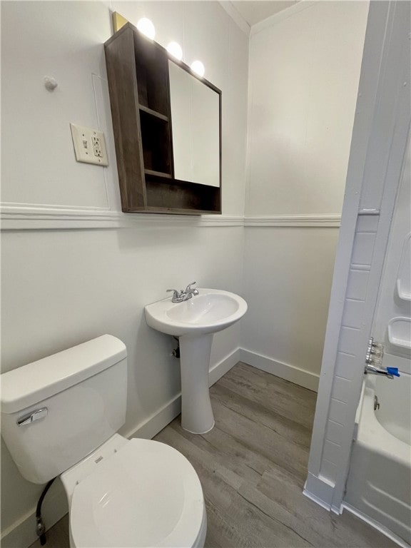 full bathroom featuring hardwood / wood-style floors, crown molding, sink, shower / washtub combination, and toilet