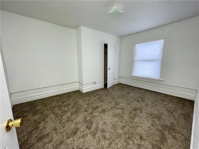 unfurnished room featuring dark colored carpet