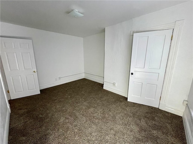 unfurnished bedroom featuring dark colored carpet and a closet