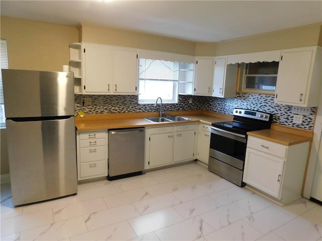 kitchen with backsplash, stainless steel appliances, white cabinetry, and sink