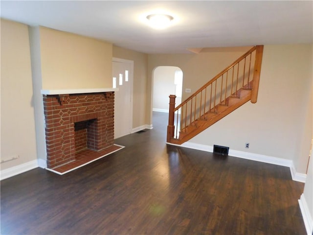 unfurnished living room with dark hardwood / wood-style flooring and a brick fireplace