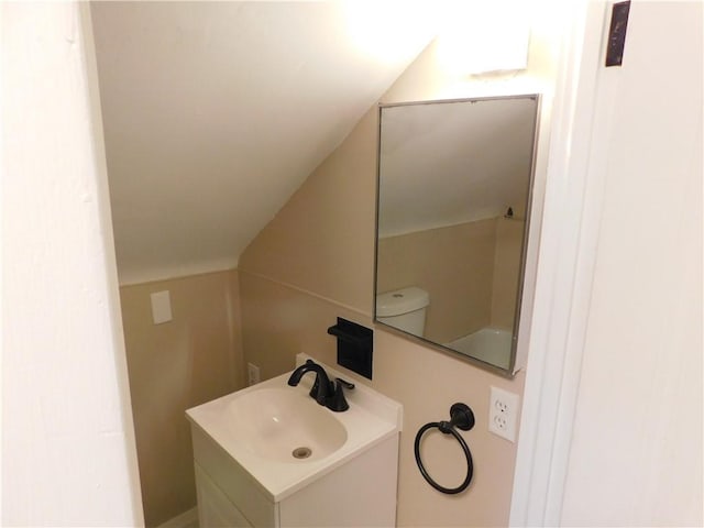 bathroom with vanity, toilet, and lofted ceiling