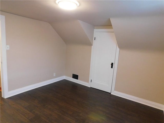 additional living space featuring vaulted ceiling and dark wood-type flooring