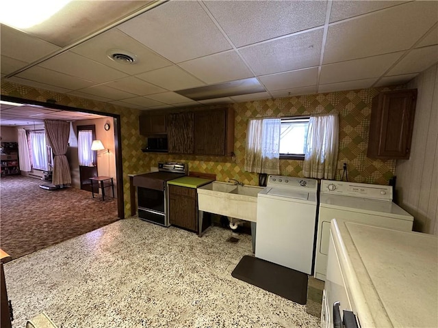 laundry area featuring washing machine and clothes dryer, light carpet, sink, and cabinets