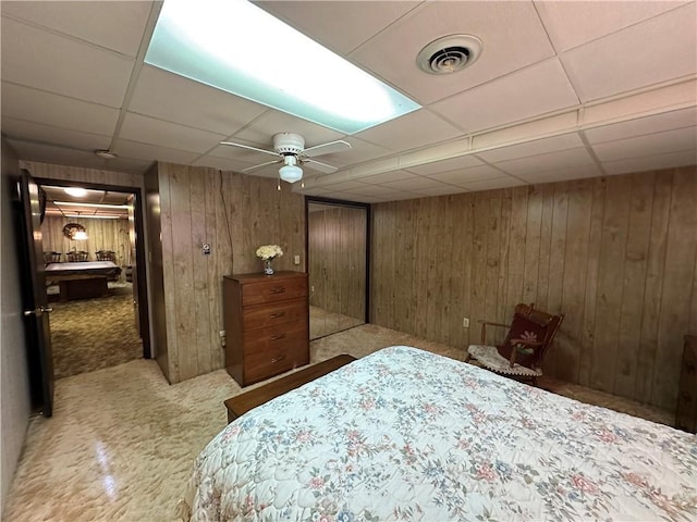 bedroom with a paneled ceiling, ceiling fan, light colored carpet, and wooden walls