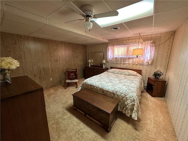 bedroom with carpet flooring, a paneled ceiling, ceiling fan, and wooden walls