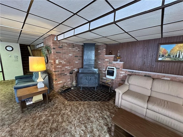 carpeted living room featuring heating unit, a wood stove, and a drop ceiling