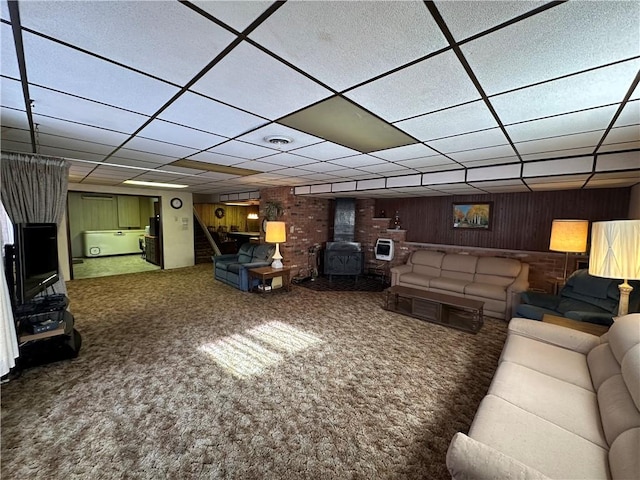 carpeted living room with wood walls and a wood stove