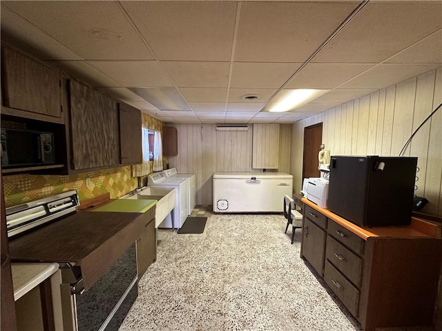 kitchen with a paneled ceiling, washer and clothes dryer, dark brown cabinetry, and sink