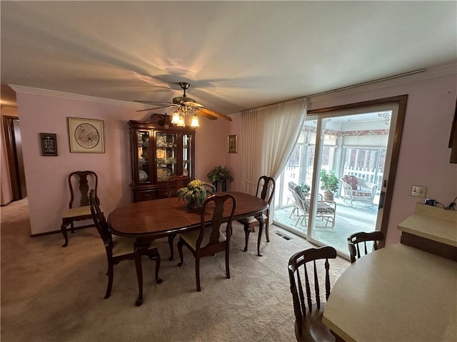 carpeted dining space featuring ceiling fan and crown molding