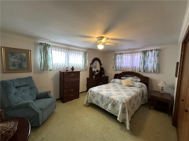 bedroom featuring a closet, ceiling fan, crown molding, and light colored carpet