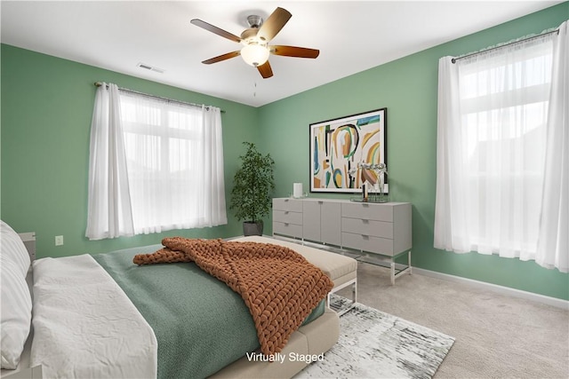 carpeted bedroom with multiple windows and ceiling fan