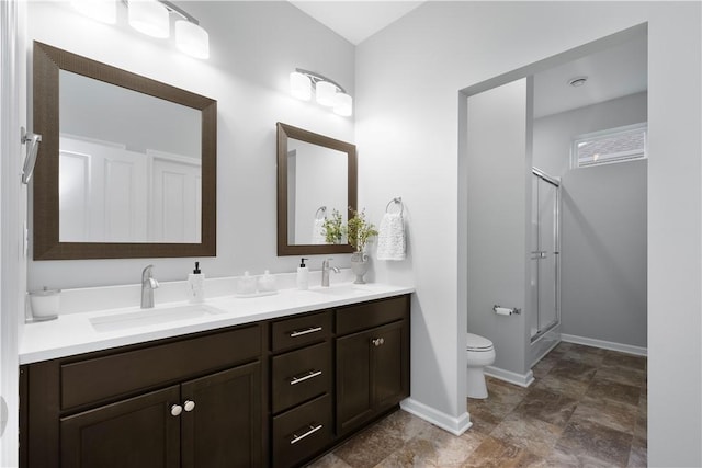 bathroom with vanity, toilet, and a shower with door