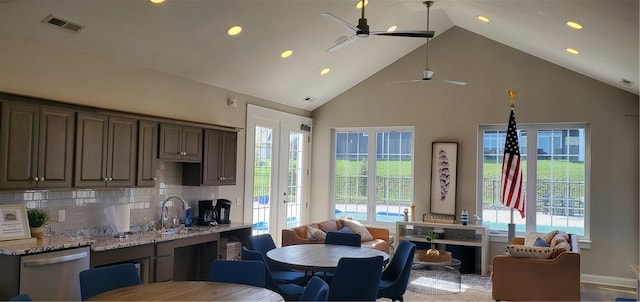 kitchen featuring decorative backsplash, light stone countertops, a wealth of natural light, sink, and dishwasher