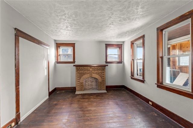 unfurnished living room with dark hardwood / wood-style flooring, a fireplace, and a textured ceiling