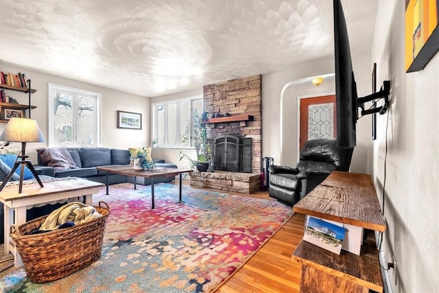 living room with hardwood / wood-style floors and a stone fireplace