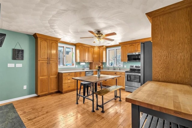 kitchen with ceiling fan, sink, appliances with stainless steel finishes, and light hardwood / wood-style flooring