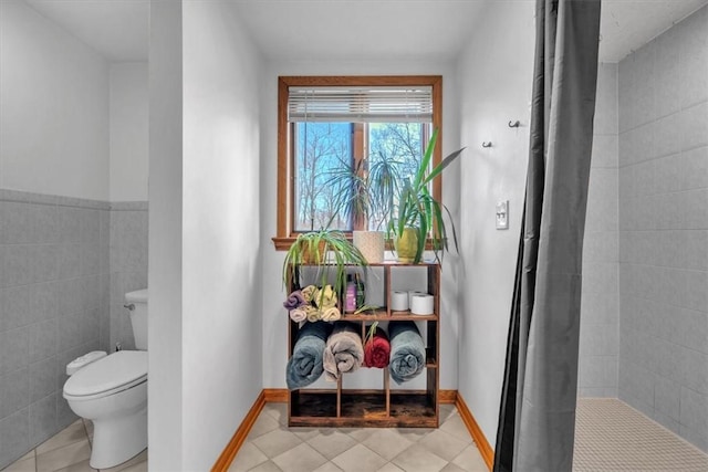 bathroom featuring toilet, tile patterned floors, and tile walls