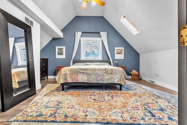 bedroom featuring light hardwood / wood-style floors, ceiling fan, and vaulted ceiling with skylight