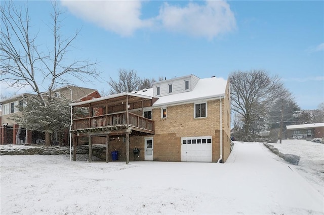 snow covered rear of property with a garage and a deck