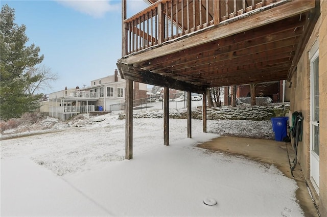 snow covered patio with a wooden deck