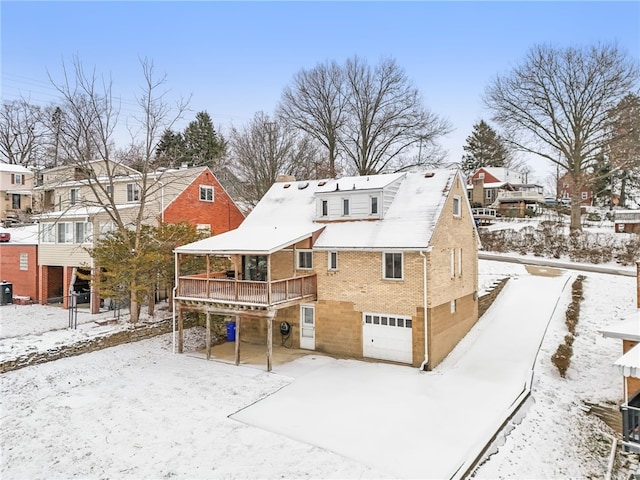 snow covered property featuring a garage and a wooden deck