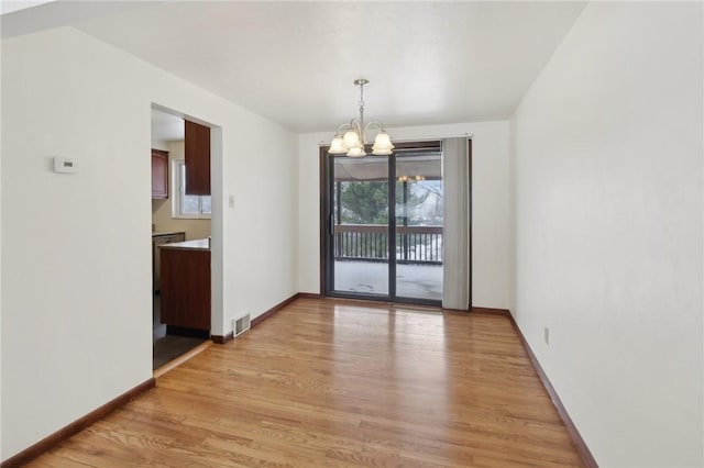 unfurnished dining area with light hardwood / wood-style flooring and an inviting chandelier