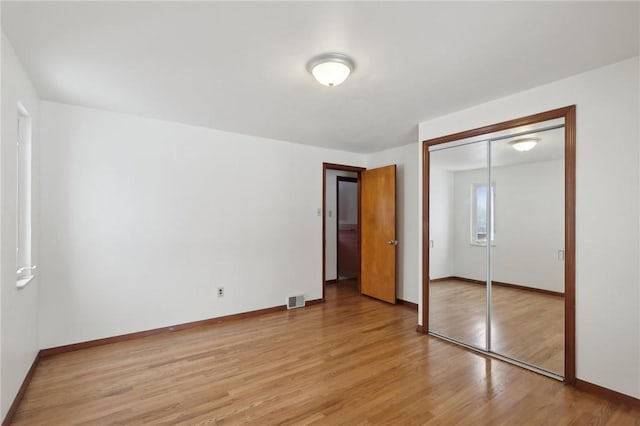 unfurnished bedroom with light wood-type flooring and a closet