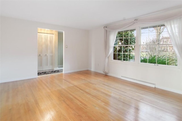 empty room with a baseboard radiator and light hardwood / wood-style floors