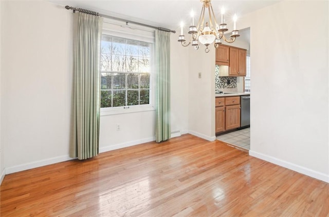 unfurnished dining area with a chandelier and light wood-type flooring