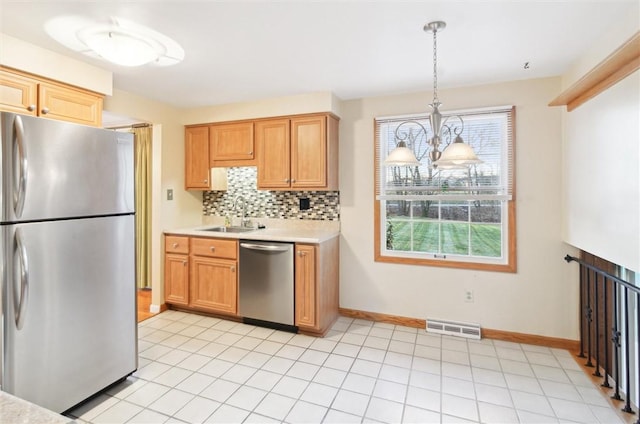 kitchen featuring sink, stainless steel appliances, an inviting chandelier, tasteful backsplash, and decorative light fixtures