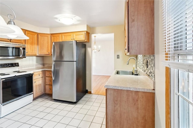 kitchen with sink, light tile patterned floors, pendant lighting, and appliances with stainless steel finishes