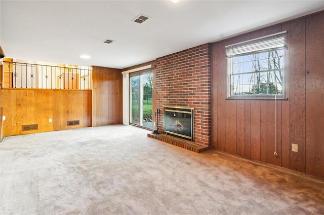 unfurnished living room with carpet, wooden walls, and a brick fireplace