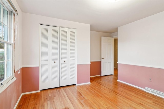 unfurnished bedroom with light hardwood / wood-style flooring and a closet