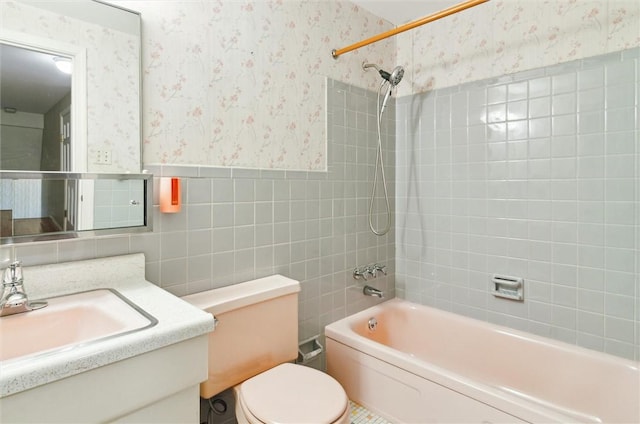 full bathroom featuring tile walls, vanity, tiled shower / bath combo, and toilet