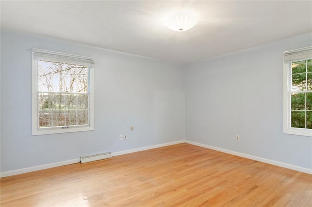 empty room with baseboard heating, plenty of natural light, and light hardwood / wood-style flooring