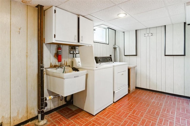 laundry area with cabinets, independent washer and dryer, sink, and wooden walls