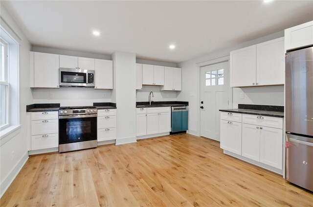 kitchen featuring a wealth of natural light, white cabinetry, light wood-type flooring, and appliances with stainless steel finishes