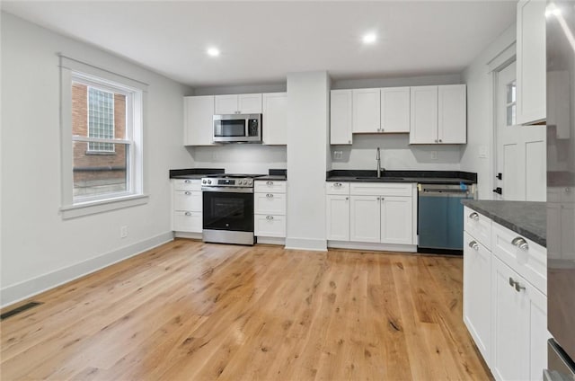 kitchen with sink, white cabinetry, stainless steel appliances, and light hardwood / wood-style flooring