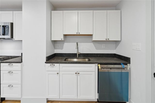 kitchen with dark stone countertops, sink, white cabinets, and stainless steel appliances