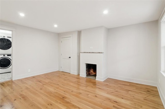 unfurnished living room with light hardwood / wood-style flooring and stacked washing maching and dryer