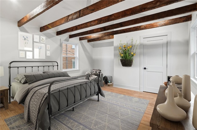 bedroom with beamed ceiling and light hardwood / wood-style flooring