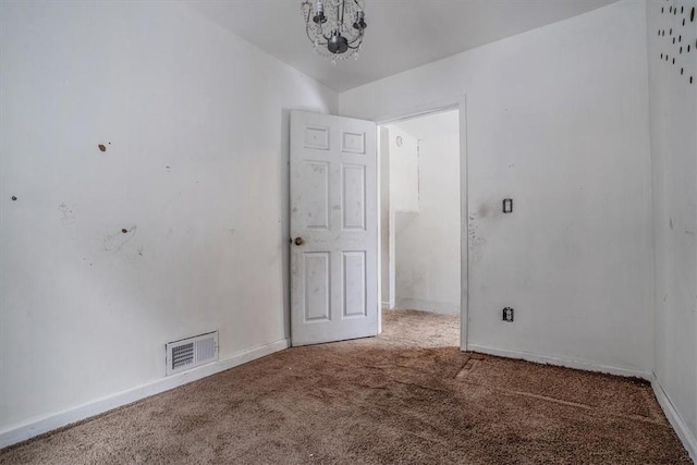 carpeted spare room with a notable chandelier