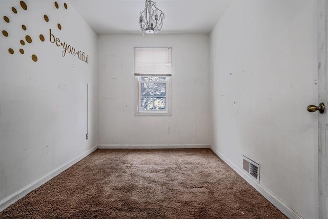 spare room featuring carpet floors and an inviting chandelier