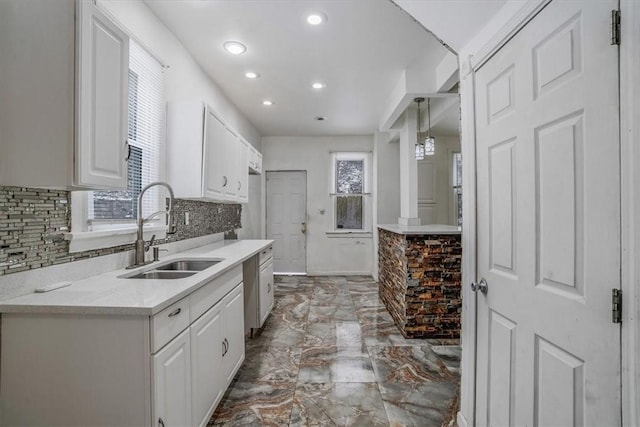 kitchen featuring white cabinetry, sink, hanging light fixtures, a chandelier, and decorative backsplash