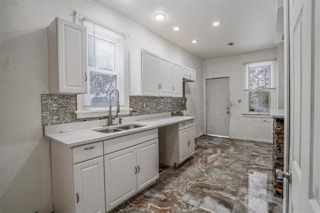 kitchen featuring white cabinets, backsplash, and sink