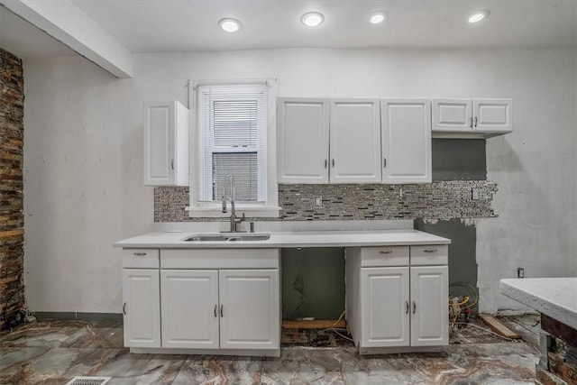 kitchen with backsplash, white cabinets, and sink